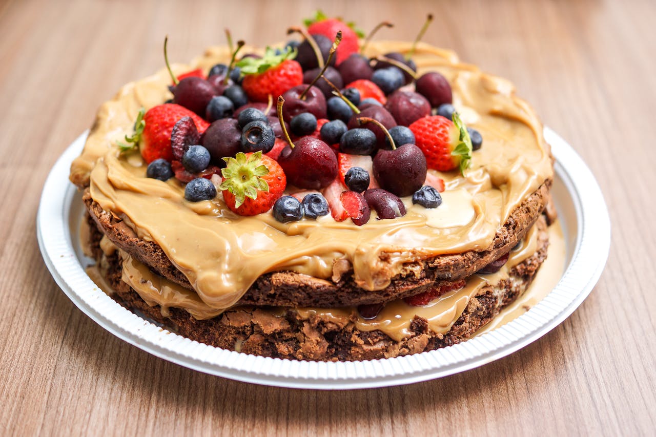 Delicious layered chocolate cake with fresh berries and peanut butter cream on a plate.